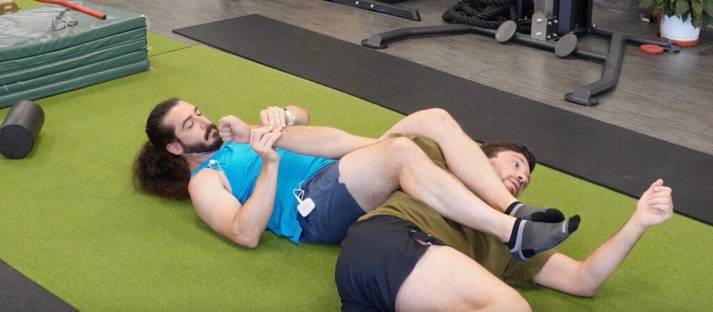 Dr. John holding Rene's right wrist and arm in between his legs in an armbar